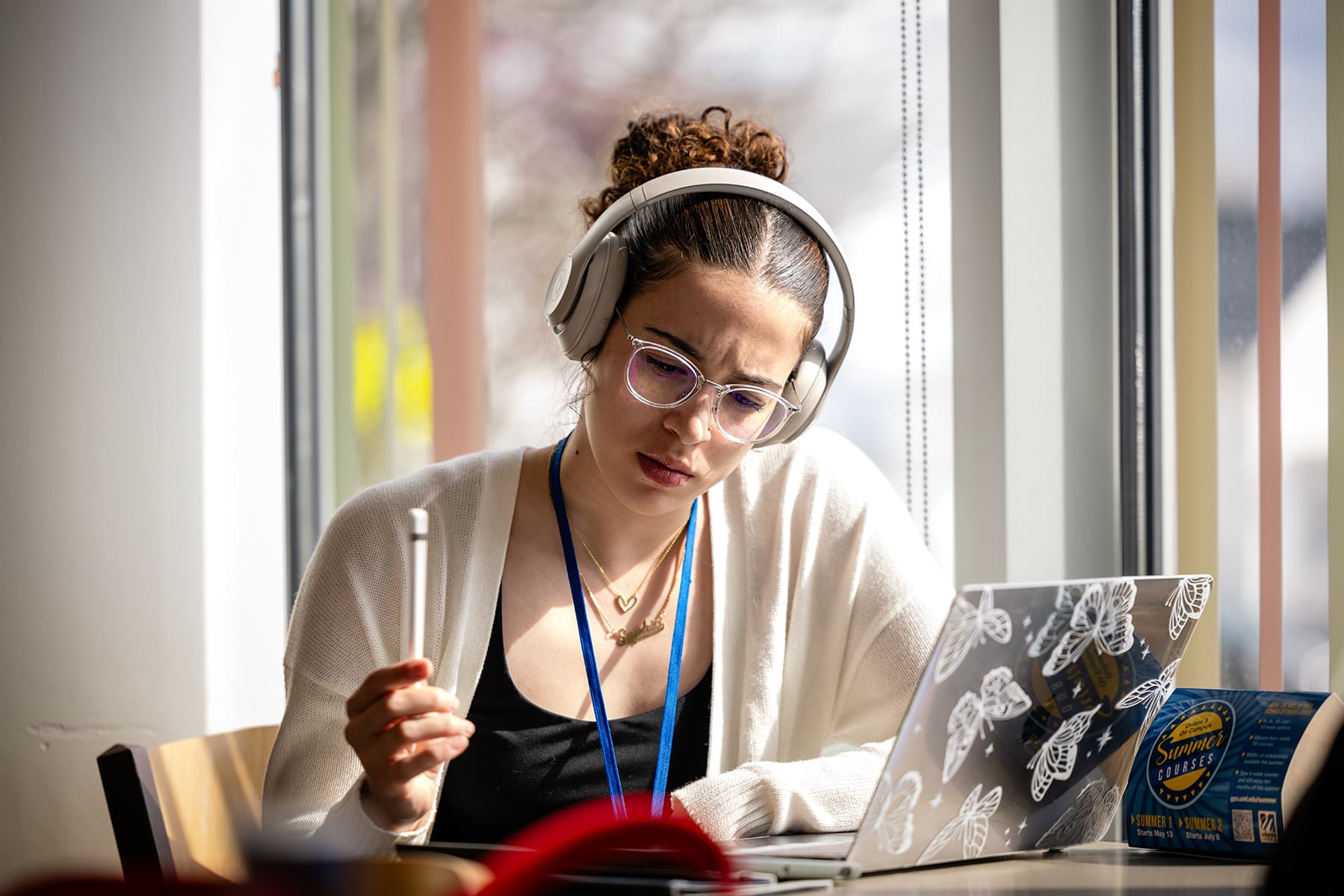 student wearing headphones sitting next to a laptop
